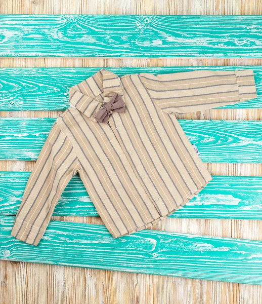 Tahta arka planda kelebek kravatlı çocuk gömleği.