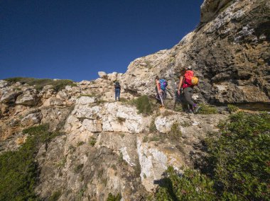 Tolleric (Cap Blanc kayalıkları), Llucmajor, Mallorca, Balear Adaları, İspanya 'nın kayalıkları üzerinde Pas des Verro' ya tırmanan yürüyüşçüler