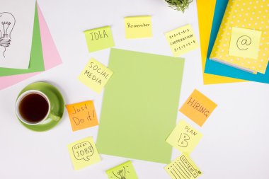 Ofis tablo Masası yeşil malzemeleri, boş not defteri, Kupası, kalem, bardak, kağıt, Büyüteç camı, çiçek beyaz arka plan üzerinde buruşuk. Üstten Görünüm