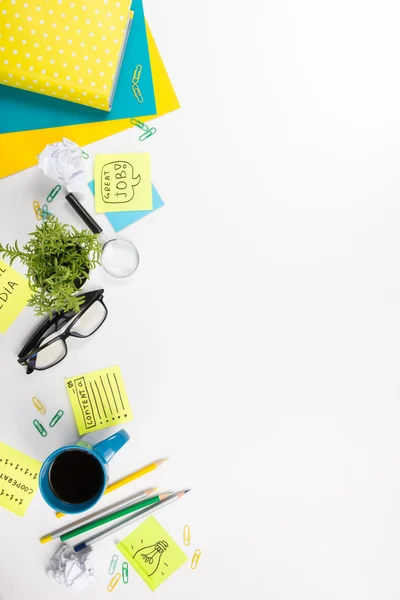 Mesa de escritório com suprimentos verdes, bloco de notas em branco, copo, caneta, óculos, papel amassado, lupa, flor sobre fundo branco. Vista superior — Fotografia de Stock