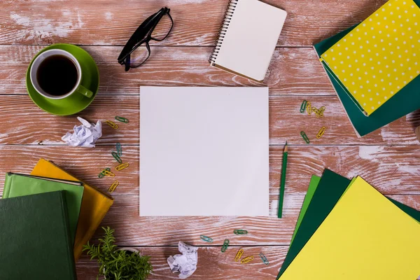 Mesa de escritório com suprimentos, bloco de notas em branco branco, copo, caneta, pc, papel amassado, flor no fundo de madeira. Vista superior — Fotografia de Stock