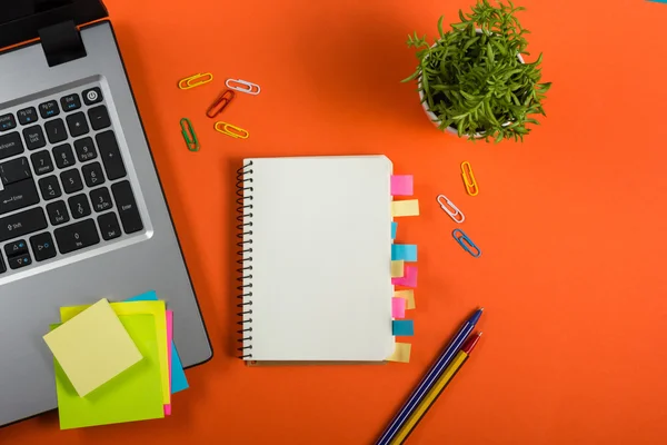 Schreibtisch mit buntem Zubehör, weißem Notizblock, Tasse, Stift, PC, zerknülltem Papier, Blume auf rotem Hintergrund. Ansicht von oben und Kopierraum für Text — Stockfoto