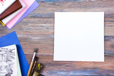 Ofis tablo büro malzemeleri, beyaz boş not defteri, Kupası, kalem, pc, buruşuk kağıt, ahşap arka plan üzerinde çiçek. Üstten Görünüm