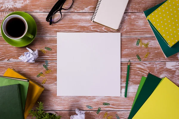 Mesa de escritório com suprimentos, bloco de notas em branco branco, copo, caneta, pc, papel amassado, flor no fundo de madeira. Vista superior — Fotografia de Stock