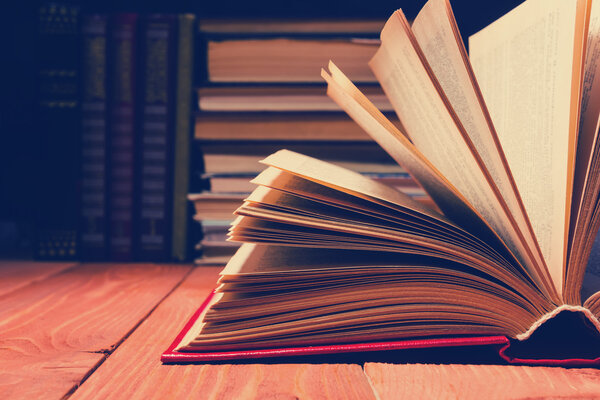 Book opened in library on wooden shelf. Education background with copy space for text. Toned photo