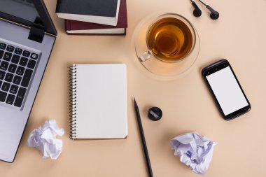 Ofis tablo büro malzemeleri, beyaz boş not defteri, Kupası, kalem, pc, buruşuk kağıt, ahşap arka plan üzerinde çiçek. Üstten Görünüm