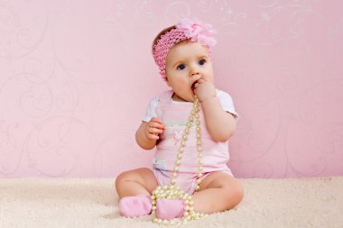 Little girl sitting on the floor holding a pearl necklace clipart