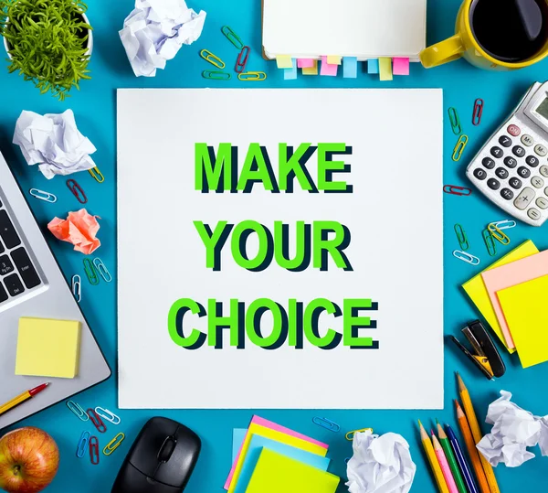 Make your choice. Office table desk with supplies, white blank note pad, cup, pen, pc, crumpled paper, flower on blue background. Top view