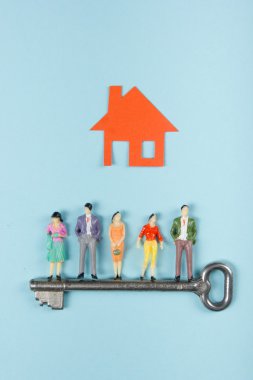 Emlak konsepti. İnşaat, inşaat. Kağıt model ev ve mavi arka plan üzerinde anahtar ile insan figürleri. Üst te. Metin için alan kopyalama.