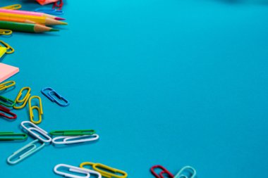 Ofis tablo Masası dizi renkli malzemeleri, beyaz boş not defteri, Kupası, kalem, pc, buruşuk kağıt, ile mavi arka plan üzerinde çiçek. Metin için en iyi görünüm ve kopya yer
