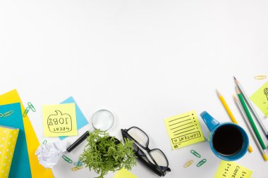 Ofis tablo Masası yeşil malzemeleri, boş not defteri, Kupası, kalem, bardak, kağıt, Büyüteç camı, çiçek beyaz arka plan üzerinde buruşuk. Üstten Görünüm
