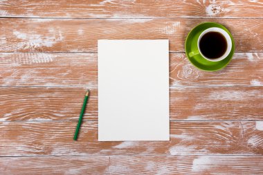 Ofis tablo büro malzemeleri, beyaz boş not defteri, Kupası, kalem, pc, buruşuk kağıt, ahşap arka plan üzerinde çiçek. Üstten Görünüm