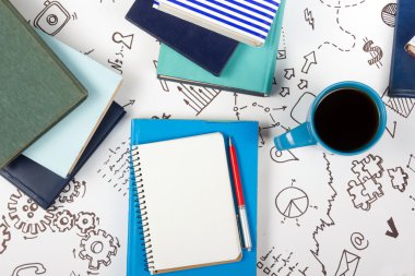 Ofis tablo Masası mavi malzemeleri, beyaz boş not defteri, Kupası, kalem, pc, buruşuk kağıt, ahşap arka plan üzerinde çiçek. Üstten Görünüm