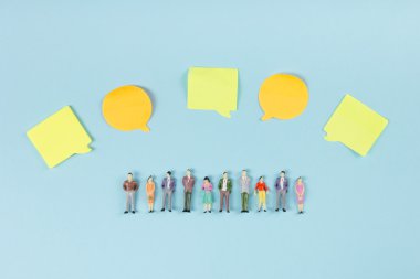 Social Media Chat Concept. Yellow blank empty chat bubble for text on blue background. Symbol of live chat. Office table desk with set of colorful supplies. Top view and copy space for ad text