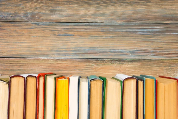 Books on grunge wooden table desk shelf in library. Back to school background with copy space for your ad text. Old hardback   no labels, blank spine