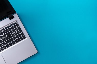 Ofis tablo Masası dizi renkli malzemeleri, beyaz boş not defteri, Kupası, kalem, pc, buruşuk kağıt, ile mavi arka plan üzerinde çiçek. Metin için en iyi görünüm ve kopya yer