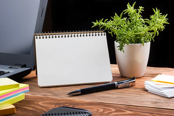 Tabell skrivbord med leveranser, vit tomt anteckningsblock, cup, penna, pc, skrynkligt papper, blomma på trä bakgrund. Ovanifrån — Stockfoto