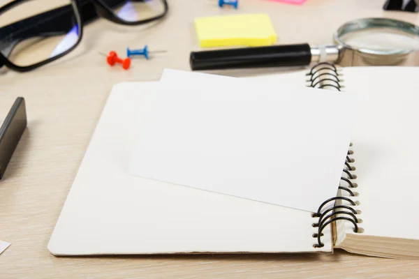 White blank open note book. Office table desk with set of colorful supplies, cup, pen, pencils, flower, notes, cards on beige   background. Top view and copy space for ad text