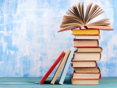 Eski vintage renkli hardback kitap istifleme, ahşap güverte masa ve sanatsal mavi arka plan üzerinde günlük ile Kompozisyon. Okula geri dön. Kopya Alanı. Eğitim kavramı.