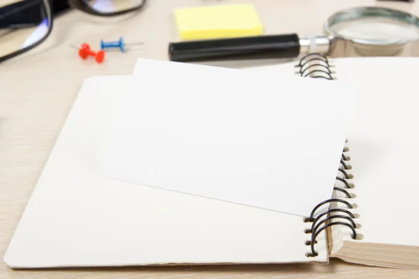 White blank open note book. Office table desk with set of colorful supplies, cup, pen, pencils, flower, notes, cards on beige   background. Top view and copy space for ad text