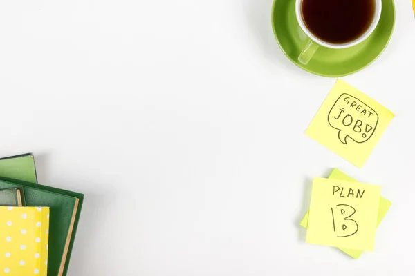 Mesa de escritório com suprimentos verdes, bloco de notas em branco, copo, caneta, óculos, papel amassado, lupa, flor sobre fundo branco. Vista superior — Fotografia de Stock