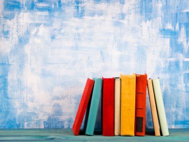 Eski vintage renkli hardback kitap istifleme, ahşap güverte masa ve sanatsal mavi arka plan üzerinde günlük ile Kompozisyon. Okula geri dön. Kopya Alanı. Eğitim kavramı.