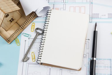 Emlak kavramı. Anahtar, kalem, küçük ev mimari Resepsiyon Masa planı zemin üzerine beyaz boş defter, ofis, banka donatımı. Kopya alanı için reklam metni, üstten görünüm.