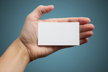 Mavi zemin üzerine beyaz kartvizit tutan el