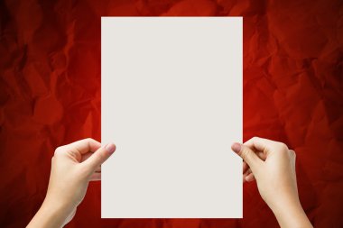 Hands holding a white paper blank isolated on red background