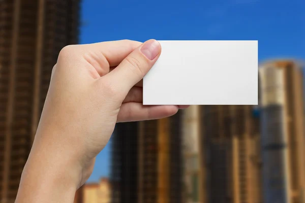 Hand holding white business card on blurred background