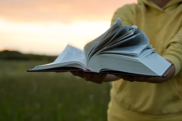 Manos femeninas sosteniendo libro de tapa dura abierto, diario contra la puesta del sol — Foto de Stock