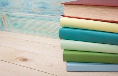 Okula dönüş. Ahşap masa üzerinde renkli kitap yığını.
