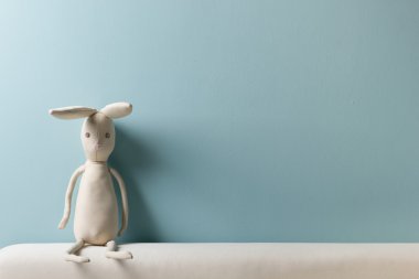 Ev iç. Çocukluk. Mavi arka plan. Oyuncak bir kanepede oturan. Kopya alanı.