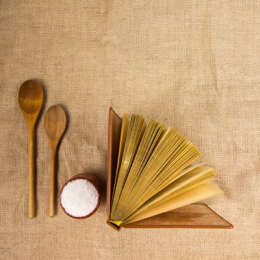 Top view of open cookbook and spoon on white background