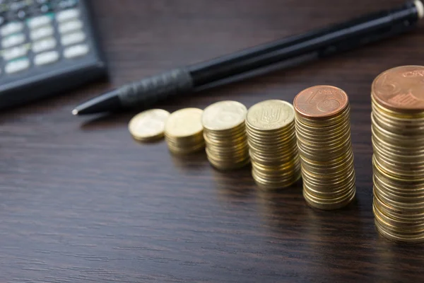 Obchodní koncept počítání peněz, kalkulačka, pero na pracovišti úřadu, úřadu. Hromady mincí na dřevěné pozadí. Finanční close-up pozadí. — Stock fotografie