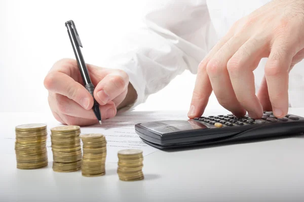 İş kavramı. İşadamı el kayıp ve istatistikleri ile çalışma, hesap makinesi üzerinde mali sonuçlarını çözümleme ve ofis işyeri, ofis işleri belgelerin imzalanması kar sayma. Sikke yığını. Finansal muhasebe - para ve hesap makinesi.