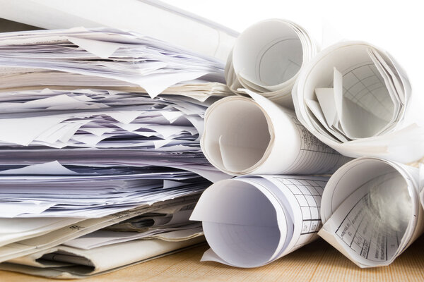 Architectural project, blueprints, blueprint rolls near checkered blank paper with pen on vintage wooden background. Construction concept. Architect workplace top view. Copy space