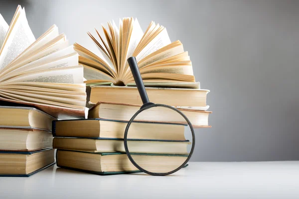 Composition with hardback books and magnifying glass. on the table. Open book, fanned pages. Back to school, copy space. Education background.