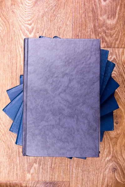 Top view of colorful hardback books on yellow background. Composition with vintage old hardback books, diary, fanned pages on wooden deck table. Books stacking. Back to school. Education background. — ストック写真