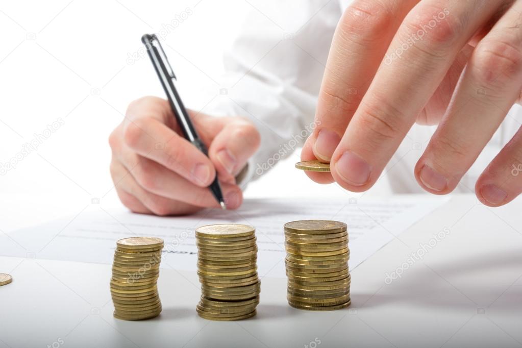 Business concept. Businessman's hand counting losses and profit working with statistics, analyzing financial results on calculator and signing documents at office workplace, office work. Stack of coins. Financial Accounting - money and calculator.