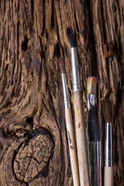 Row of artist paintbrushes on old natural grunge wooden background