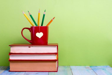Back to school. Composition with old vintage hardback books and red cup, heart, pencils clipart