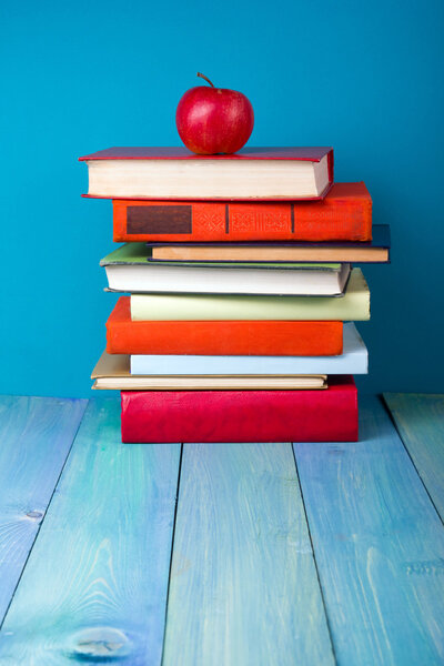 Stack of colorful books, grungy blue background, free copy space.