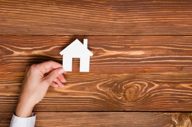 Hands holding green paper house figure models arrows on white background. Concept for comparision of real estate houses pricing Real Estate Concept. Top view, copy space. Eco house