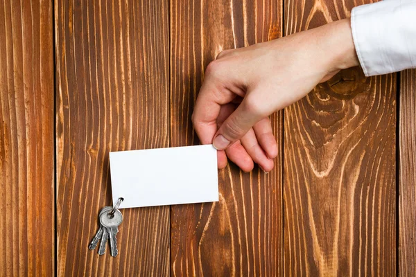 Silver key with house figure and blank business card on wooden background. Real Estate Concept. Top view — ストック写真