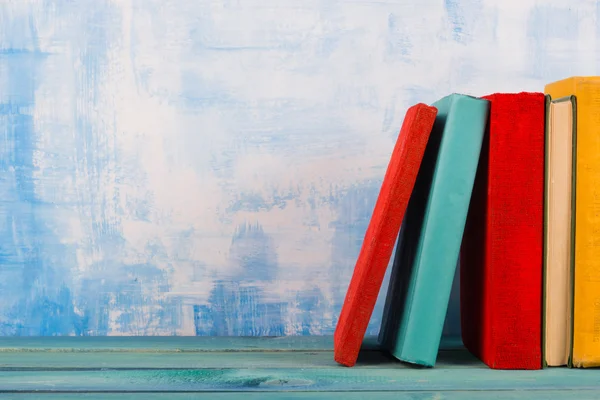 Eski renkli ciltli kitaplar vintage, diary ahşap güverte tablo ve sanatsal mavi arka plan ile kompozisyon. Kitap istifleme. Okula dönüş. Uzay kopyalayın. Eğitim arka plan