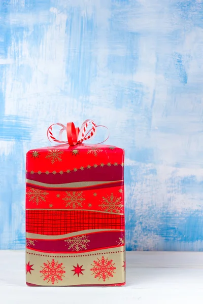 Gift box with red bow on vintage blue wooden table background. Christmas decoration on grunge blue artistic painted background. Winter holidays concept. Copy space. Merry Christmas and Happy New Year! — Zdjęcie stockowe