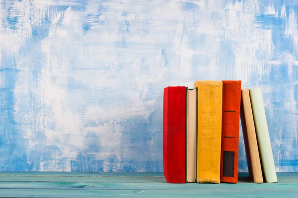 Komposition mit alten Vintage bunten gebundenen Büchern, Tagebuch auf Holzdecktisch und künstlerisch blauem Hintergrund — Stockfoto