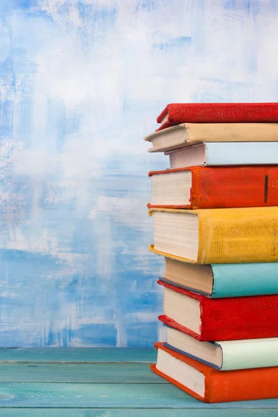 Komposition mit alten Vintage bunten gebundenen Büchern, Tagebuch auf Holzdecktisch und künstlerisch blauem Hintergrund — Stockfoto