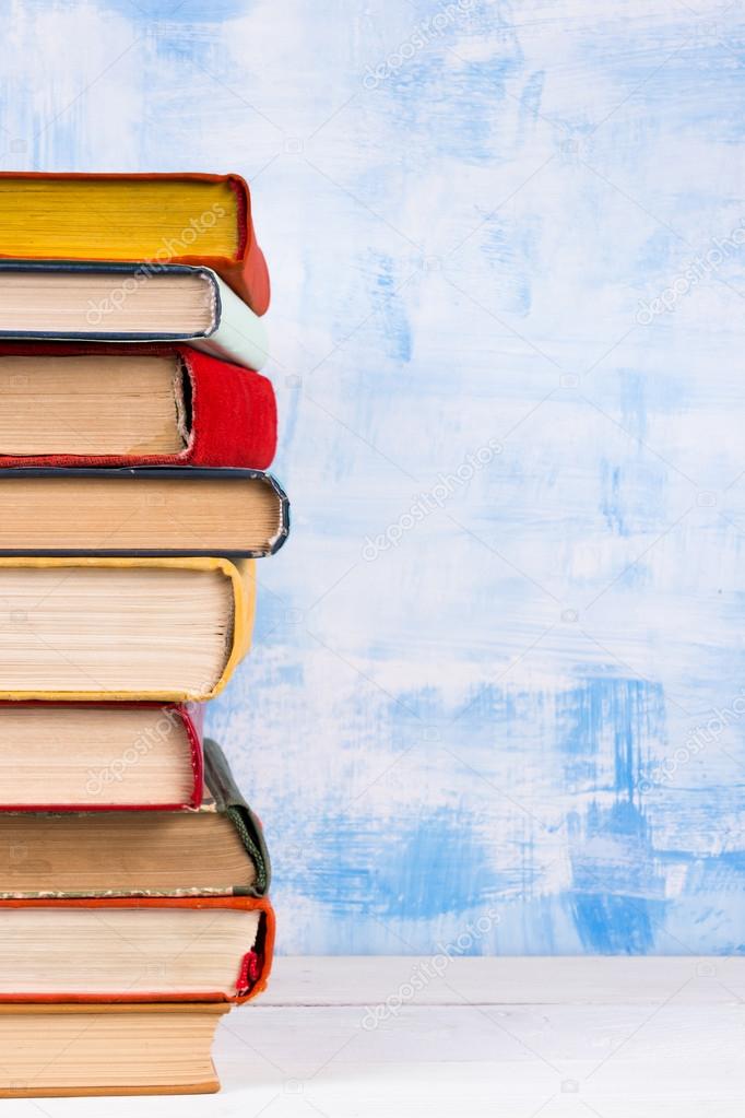 Composition with old vintage colorful hardback books, diary on wooden deck table and artistic blue background. Books stacking. Back to school. Copy Space. Education background